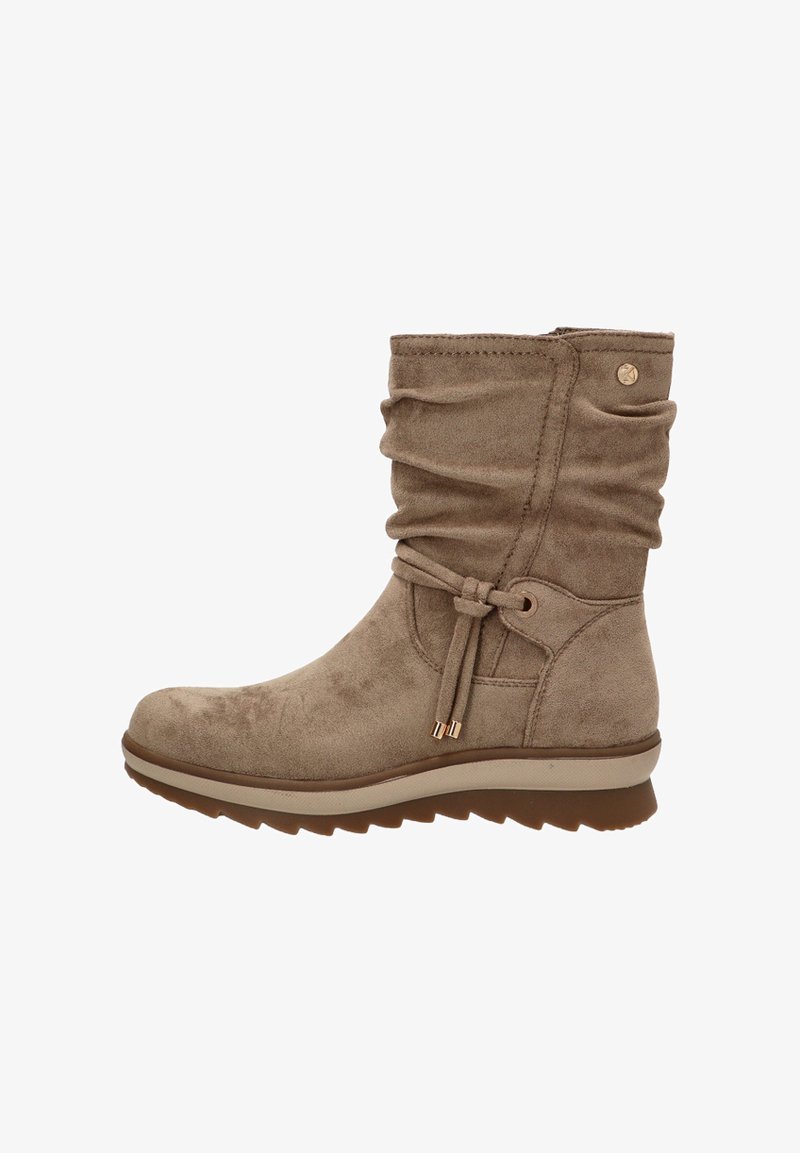 Botín de ante beige con un diseño suelto, lazo decorativo y parte superior texturizada. Presenta una suela de goma en contraste y detalles dorados.