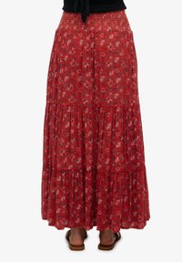 Falda larga floral roja con cintura fruncida, diseño por capas, tela ligera, adornada con pequeñas flores azules y blancas.