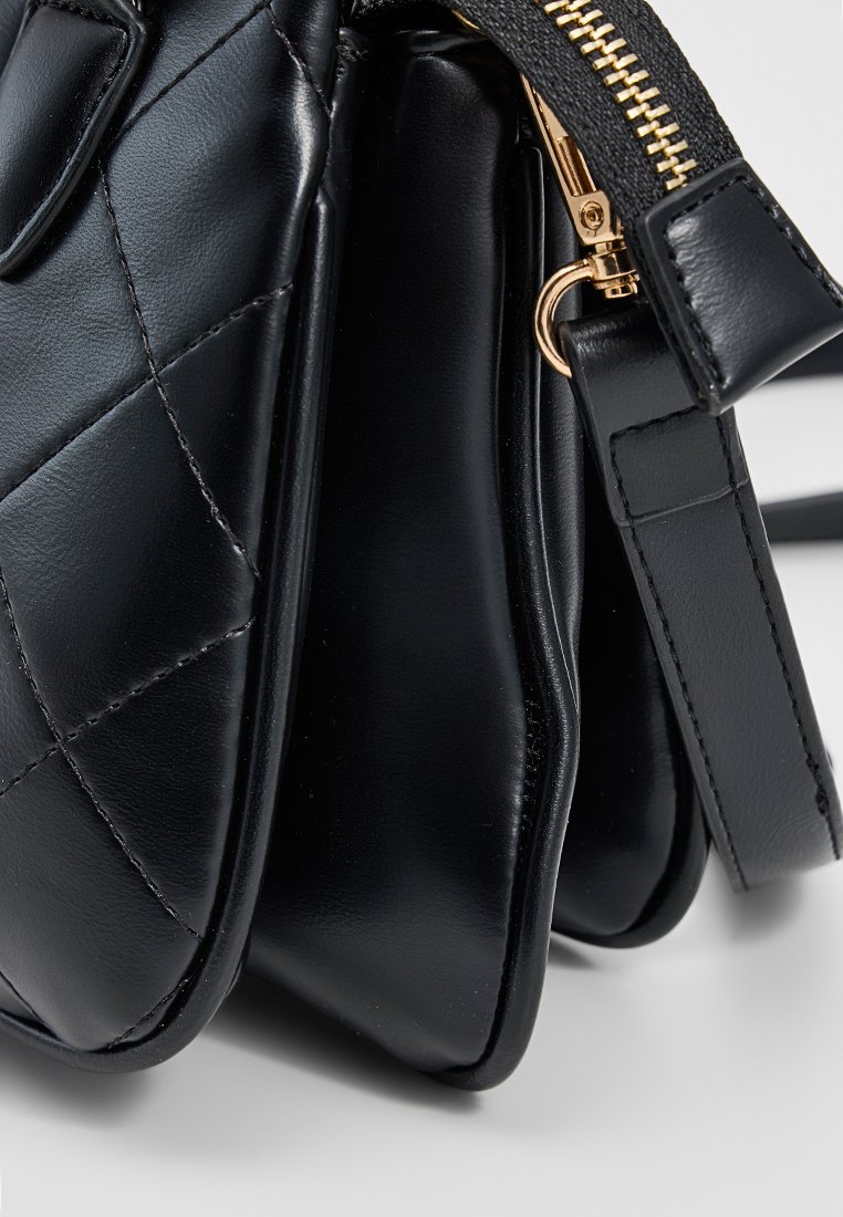 Schwarze, gestepptes Lederhandtasche mit goldfarbenem Reißverschluss, gestepptem Tragegurt und mehreren Fächern.