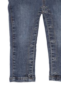 Pantaloni in denim di colore blu scuro, con chiusura a bottone a pressione lungo la parte interna della gamba, e design a gamba dritta con orlo risvoltato.