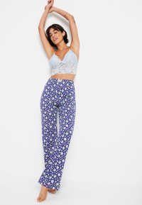 Ανοιχτό μπλε δαντελένιο σουτιέν και φλοράλ παντελόνια με φάσ�ες σε μωβ απόχρωση με πράσινες λεπτομέρειες. Το ύφασμα φαίνεται μαλακό με χαλαρή εφαρμογή.