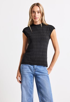 Top de punto negro de manga corta con un patrón sutil, ajustado en la cintura, combinado con unos vaqueros de pierna ancha de color azul claro, creando un look casual.