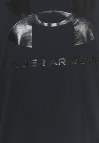 Tela negra con el logotipo brillante en negro de Under Armour y texto impreso en la superficie.