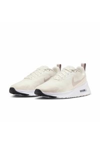 Nike sneakers met een lichtbeige bovenkant, gestructureerd ontwerp, witte tussenzool en zwarte rubberen buitenzool met een zichtbare luchtunit.