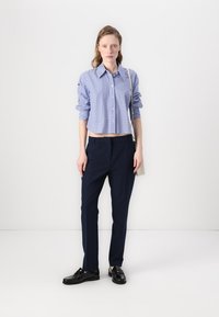 Light blue striped cropped shirt with a collar and buttons, paired with dark navy straight-leg trousers and black lace-up shoes.