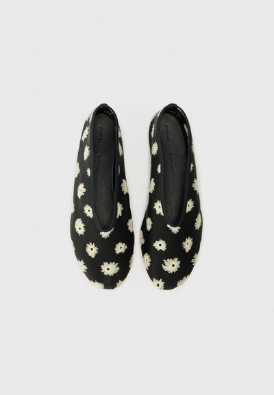 Bailarinas de tela negra con patrón floral blanco, punta redondeada, bordes elásticos y textura suave. Diseño de suela plana y sencilla.