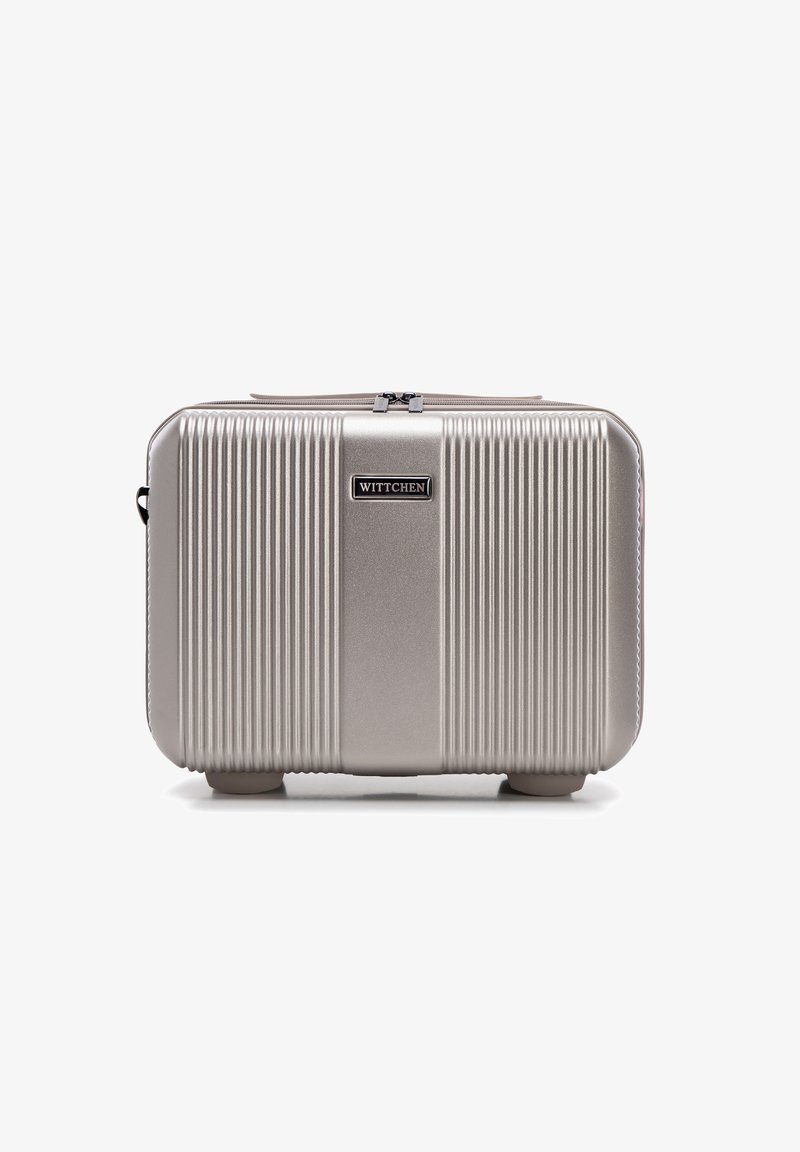 Beauty case rigido argentato con scanalature verticali, un pannello centrale liscio e una placca con logo, chiusura a zip e angoli arrotondati.