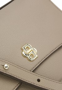 Clutch in pelle texturizzata beige con accentuazione del logo in oro, dotato di una tracolla staccabile e chiusura a scatto, che mette in evidenza un design elegante.