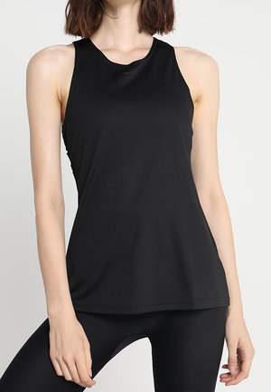 Kobieta w czarnej bezrękawnikowej sportowej bluzce i dopasowanych legginsach, pozująca z jedną ręką opartą na udzie.