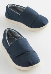 Navyfarbene Canvas-Slipper mit weißen Gummisohlen, ausgestattet mit gestreifter Stoffauskleidung und einem Klettverschlussriemen über dem Obermaterial.