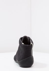 Black ankle boot with textured fabric upper, rounded toe, and rubber sole. Features a zipper on the back for easy wear.