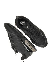 Zwarte sportieve schoenen met een bovenwerk van mesh en een gestructureerde rubberen zool. Opvallende details zijn de verstevigde zijkanten en een metalen accent.