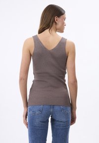 Pruun vöötohtrast tank ülikond V-kaelusega ja liibuva disainiga, koos siniste denimite pükstega. Minimalistlik, struktureeritud kangas tõstab esile vertikaalsed jooned.