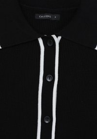 Schwarzes, geripptes Poloshirt mit weißem Saum, ausgestattet mit einem Knopfverschluss und einem Etikett, auf dem "CALLIOPE S" steht. Weicher Stoff mit einer strukturierten Oberfläche.