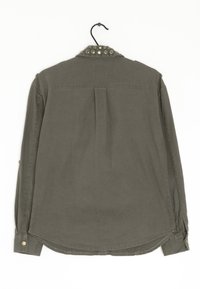 Oliwkowa koszula z długim rękawem ze zdobionym kołnierzykiem, z plisą z tyłu i mankietami zapinanymi na guziki. Wykonana z lekkiego materiału.