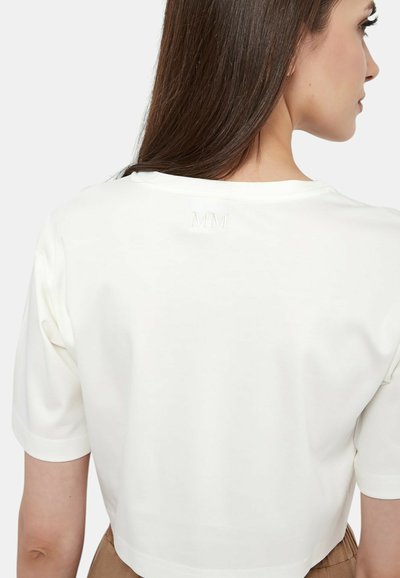 T-shirt bianco corto con maniche corte, caratterizzato da un collo rotondo e un dettaglio ricamato "MM" sul retro. Tessuto dalla texture liscia.