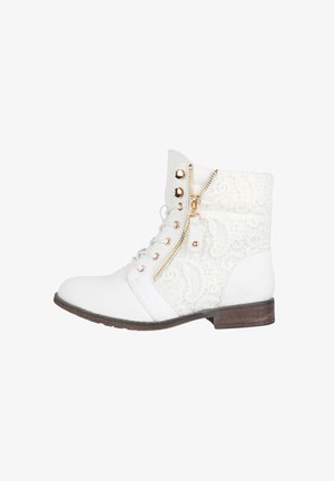 Witte enkelboots met kantpaneel, gouden ritsdetails en ronde neus. Heeft een platte, gestructureerde bruine zool en decoratieve gouden vetertjes.