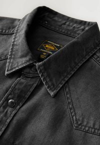Czarna koszula z denimu z wyciąganym kołnierzykiem, czarnymi guzikami i fakturowaną powierzchnią. Metka z napisem "Durable 2000s", rozmiar M, wyprodukowano w Indiach.