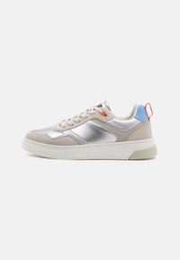Baskets avec une tige synthétique argentée, des accents en suède beige clair, une semelle de couleur crème et un onglet de talon coloré en bleu et orange.