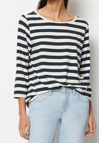 Marinblå och vit randig långärmad topp med rund halsringning, tillverkad av mjukt tyg, kombinerad med ljusblå jeans.