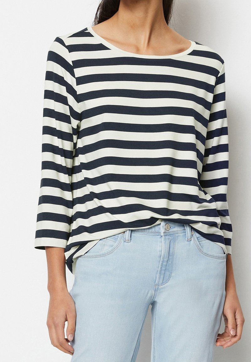 Marinblå och vit randig långärmad topp med rund halsringning, tillverkad av mjukt tyg, kombinerad med ljusblå jeans.