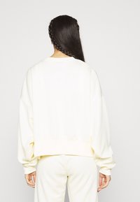 Light yellow oversized sweatshirt with dropped shoulders and ribbed hem. Soft texture and relaxed fit, paired with matching bottoms.