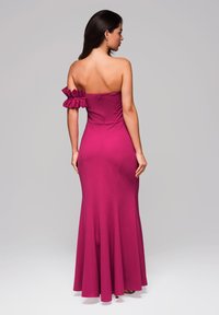 Fuchsiová off-shoulder šaty s volánkovým detailem na jednom rukávu, úzkým korzetem a rozšířenou sukní. Vyrobeno z elastického materiálu s hladkou texturou.