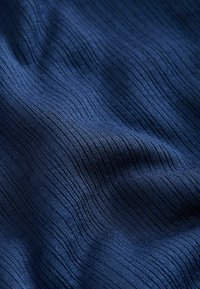Dark blue fabric with fine vertical ribbed texture and subtle folds creating soft shadows and highlights.