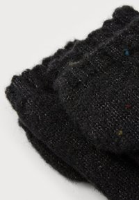 Schwarze gestrickte Socken aus weicher Wolle. Sie haben einen gerippten Bund und ein strukturiertes Muster mit bunten Sprenkeln im Material.