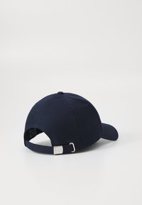 Navy blue cotton baseball cap with a curved brim, adjustable strap, and silver metal hardware featuring a small label marked "EA7."