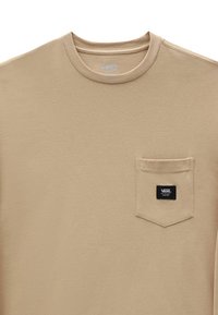 Beige T-shirt med rund hals og brystlomme, som har et sort Vans-logo patch.