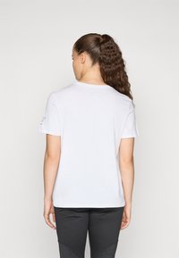 White cotton t-shirt with short sleeves, a round neckline, and a plain back. Features subtle printed text on the left sleeve.