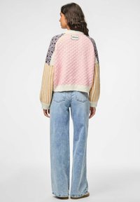 Gebreide trui met een mix van pastelroze, blauw en gele panelen, met een gestructureerde achterkant en brede gestreepte mouwen. Gepaard met een lichte denim.
