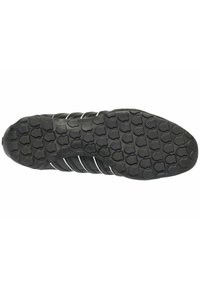 Schwarze Sportschuhsohle aus strukturiertem Gummi, mit einem gemusterten Profil für Grip und drei weißen Streifen an der Seite.