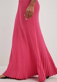 Rosa plissierte Maxirock mit gerippter Textur, ausgestattet mit einem ausgestellten Saum und glatter Oberfläche. Der Stoff fällt elegant bis zum Boden.