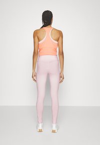 Lättvikts orange sporttopp med vit kant, kombinerad med figursydda rosa leggings. Slät struktur och racerback-design.