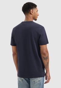 Navyblauw T-shirt met korte mouwen, ronde hals, gemaakt van zachte katoen. Heeft een subtiele logo en platte naden; gedragen met lichte spijkerbroek.