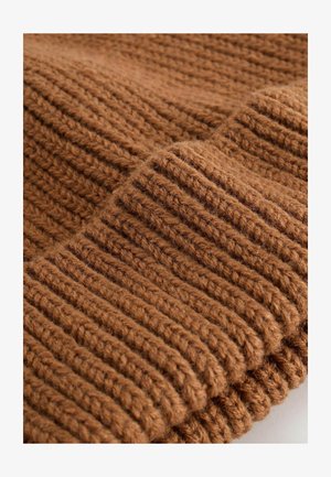 Braun gestrickter Stoff mit einer gerippten Textur, der ausgeprägte, dicke Garnstränge und eine gefaltete Kante aufweist, was ein gemütliches Aussehen verleiht.