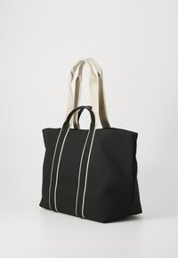Borsa tote nera con accenti a righe beige, dotata di due manici lunghi e un design strutturato. Realizzata in tessuto resistente, con una finitura elegante.