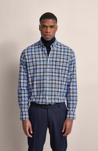 Camicia a quadri blu e nera con colletto, taschino singolo sul petto e polsini abbottonati, abbinata a pantaloni scuri. Tessuto dalla texture liscia.