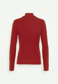 Roter Rollkragenpullover mit langen Ärmeln, von hinten präsentiert, mit einer subtilen V-förmigen Nahtdetails unterhalb des Kragens.