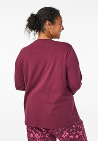 Maroon long-sleeve top with a round neckline and a relaxed fit, paired with floral-patterned pants in shades of pink and maroon.