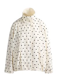 Veste crème à manches longues avec des pois noirs, col montant, fermeture à boutons sur le devant, ourlet et poignets élastiqués.