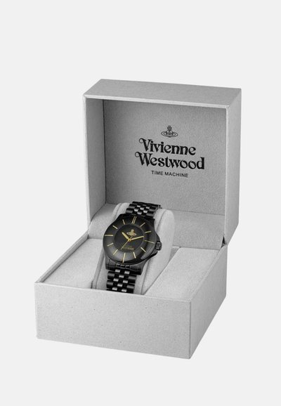 Orologio nero con quadrante rotondo testurizzato, dettagli in oro e cinturino in metallo nero, presentato in una scatola grigia con il nome del marchio stampato all'interno.
