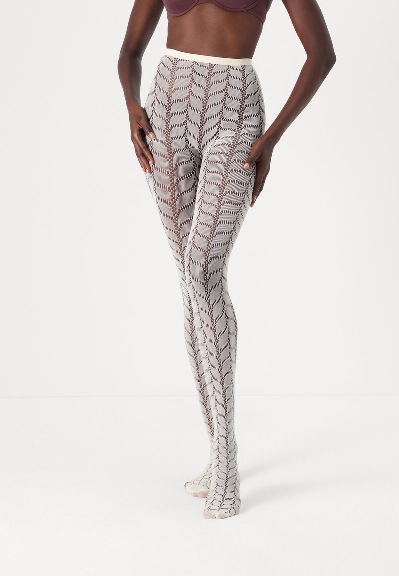 Patterned leggings in a light hue featuring a geometric design with chevrons, crafted from a semi-sheer material with a soft texture.