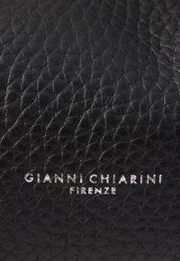 Crna teksturirana koža s vidljivim uzorkom zrna; na dnu se nalazi srebrni uvezeni tekst "GIANNI CHIARINI FIRENZE".