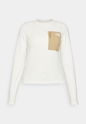 Valkoinen pitkähiha shirt, joka on valmistettu teksturoidusta kankaasta, jossa on beige laukkutasku, jossa on naru ja logo.