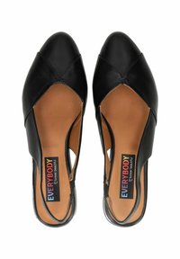 Zapatos negro de piel con tiras traseras, laterales abiertos, punta afilada y un acabado suave. Cuenta con una plantilla marrón con marca.