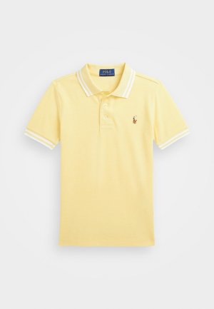 Polo tričko zo svetlo žltého bavlneného materiálu, s klasickým golierom, dvojitým zapínaním na gombíky a bielymi pruhmi na rukávoch. Vyšívané logo.