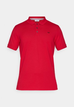 Punane puuvillane polo särk krae, kolme nupuga nööpide rida, lühikesed varrukad ja väike broderitud logo vasakul rinnal.